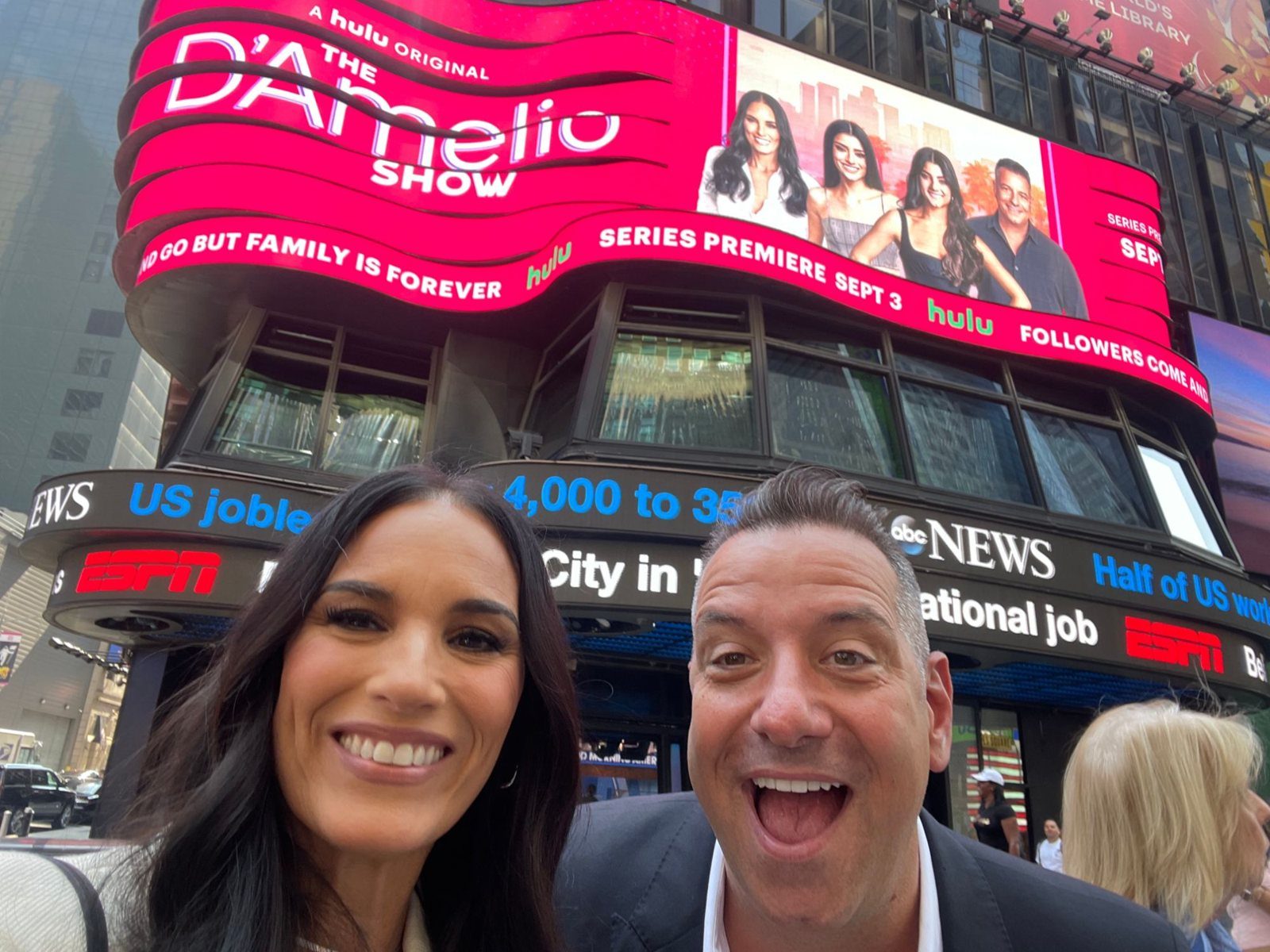 Marc and Heidi D'Amelio under The D'Amelio Show billboard in Times Square